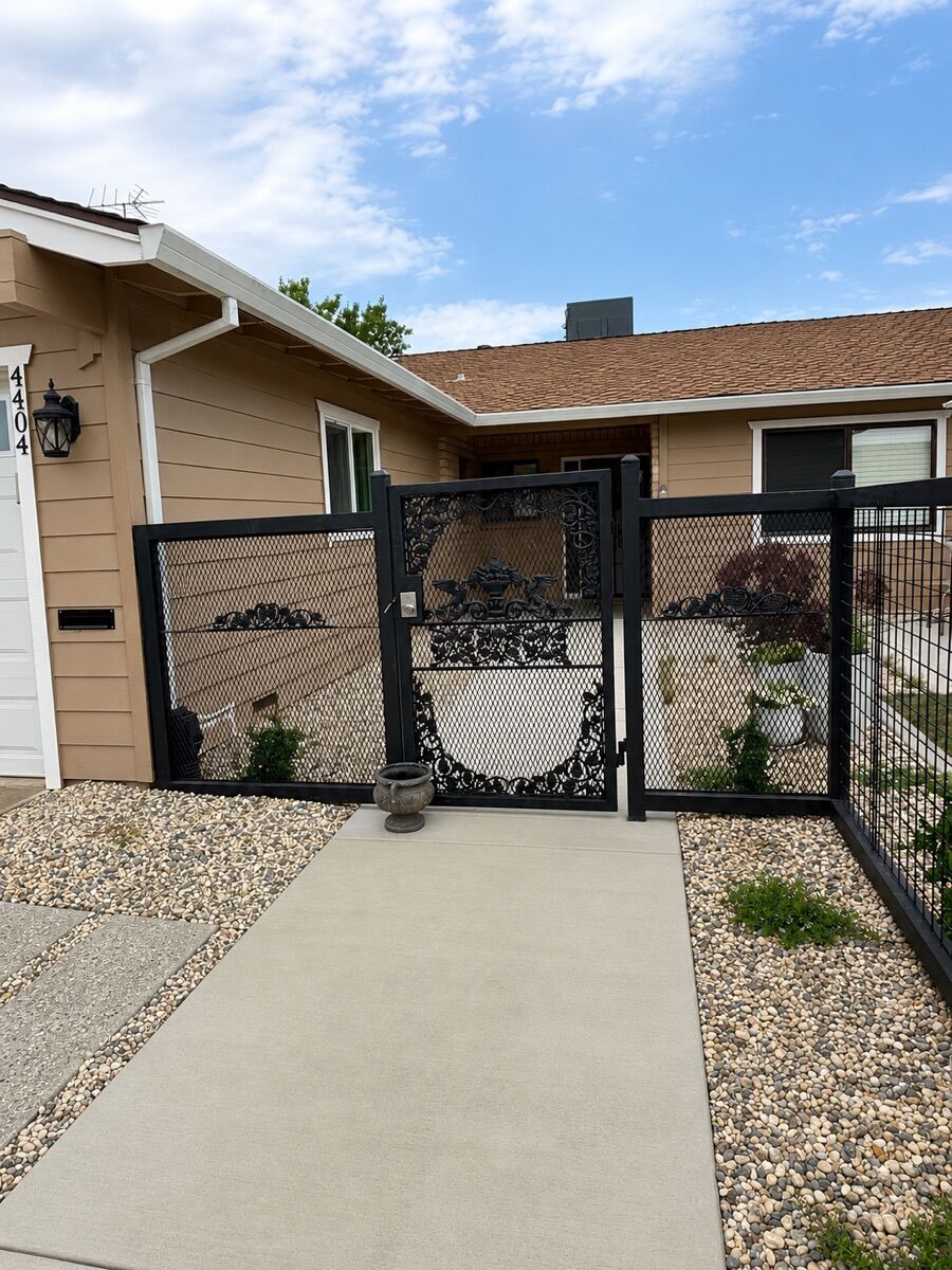 Custom ornate wrought-iron entry gate with hand-forged cast scrollwork by Iron Caz Fencing