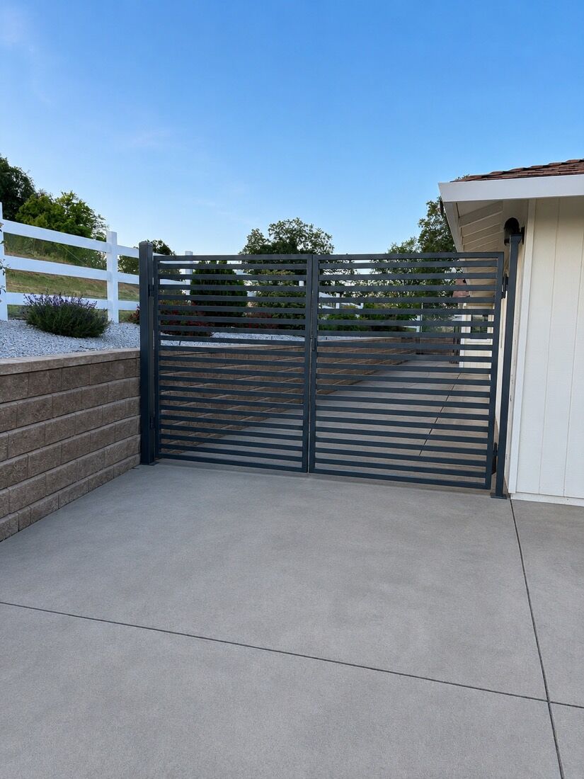 Gray horizontal-slat double gate beside a retaining wall